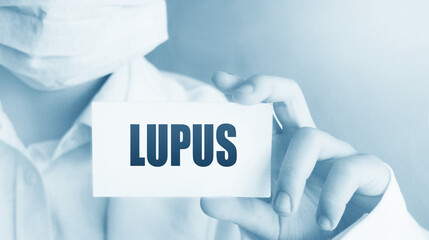 Doctor's hand shows the card with word lupus. Medical concept