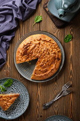 Delicious pie with meat and potatoes with a crispy crust on a blue plate on a wooden table