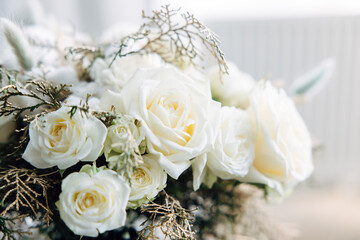 wedding bridal bouquet. Flower arrangement of white roses, thuja branches, cotton and spikelets. Winter decor concept. Close-up and selected focus.
