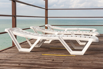 Group of Beautiful white plastic sunbeds is on the beach by sea