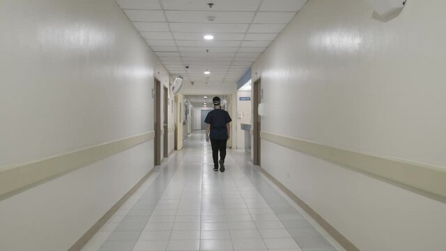 Static Back View Shot of Male Young Lonely Doctor Walking Through Empty Clinic Corridor in the Evening, 4k