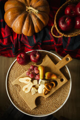 cheese plate with fruit top view. autumn fruits and cheese on a wooden board. pear, grapes, apples and hard cheese. big pumpkin and seasonal food