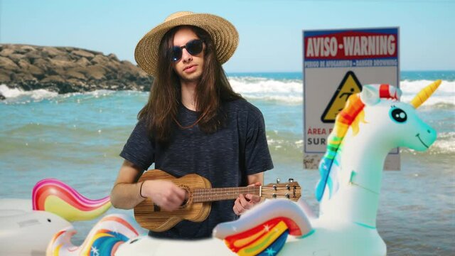 Summertime Beach Fun Male Teenager Playing Ukulele, Funny Scene. Long haired male teenager is playing ukulele during beach vacations. Medium shot