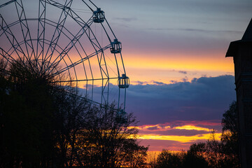 ferris wheel cabins on the background of a beautiful sunset. clouds painted in different colors by the setting sun. landscape in the golden hour