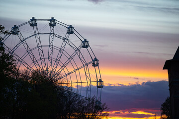 ferris wheel cabins on the background of a beautiful sunset. clouds painted in different colors by the setting sun. landscape in the golden hour