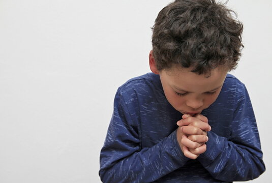 boy praying to God with hands together on white background stock photo