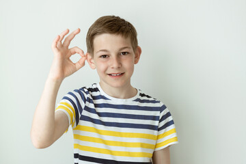 Portrait of happy handsome teen boy on white wall background with emotional gesture