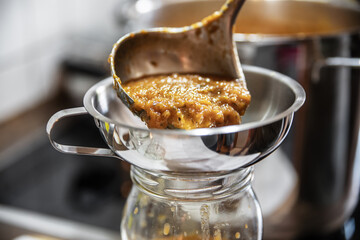fresh cooked vegetable sauce will be filled through an funnel into a glass