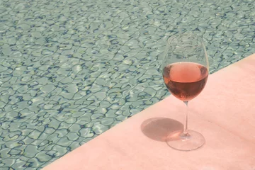 Tuinposter Crystal goblet with rose wine on the edge of a swimming pool. High class people drink concept. © Horacio Selva