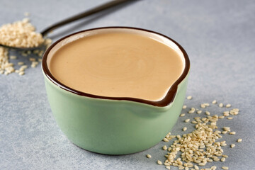 Tahini paste in bowl with sesame seeds. Close up