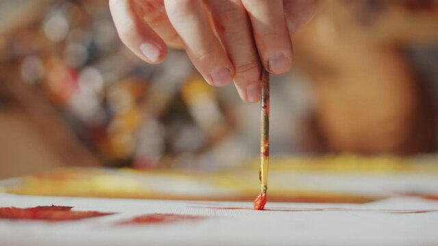 Close up selective focus shot of hand of unrecognizable male artist painting on canvas with brush