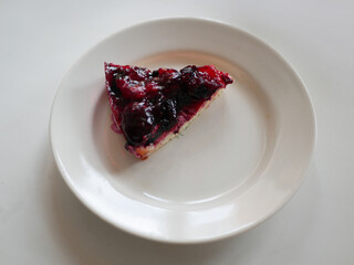 A piece of berry pie on a white plate. White background
