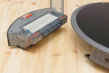 Human takes out a dust container in a robotic vacuum cleaner.