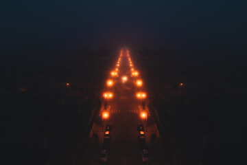 Road lit by street lamps shrouded in fog