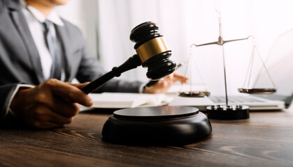 Justice and law concept.Male judge in a courtroom with the gavel, working with, computer and docking keyboard, eyeglasses, on table in morning light