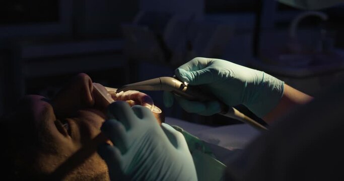 Close-up male face with an optragate on his mouth who is having dental air-drying teeth by the dentist who is using an air handpiece.
