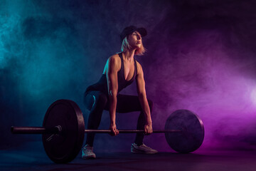 Side view of female bodybuilder doing deadlift using barbell. Sr