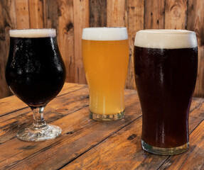 Alcoholic drinks. Closeup view of three glasses with different kinds of beers, black, red and golden, on the pub wooden table.