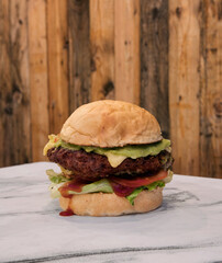 American food. Closeup view of a delicious Fried chicken burger on the restaurant white marble table with a wooden background. 