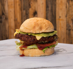American food. Closeup view of a delicious Fried chicken burger on the restaurant white marble table with a wooden background.