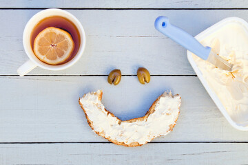 Freshly baked bagel with cream cheese and tea. Smiley face.