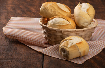 breads in a basket on checkered tablecloth over rustic wood, black background, selective focus.