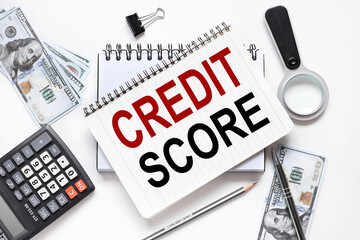 CREDIT SCORE. notebook on white workspace. near the notepad dollar bills and a calculator