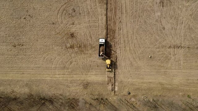 Loader excavator loads the ground in the truck at the road construction.