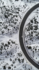 Fototapeta na wymiar Aerial view of road going through the beautiful snow covered landscape.