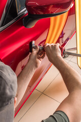 The technician removes dents on the car using the method without painting. PDR. Car body repair. - 431058175