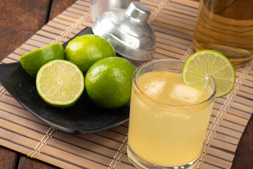 Brazilian drink caipirinha, glass of caipirinha, bottle of cachaça, cocktail shaker and lemons on...