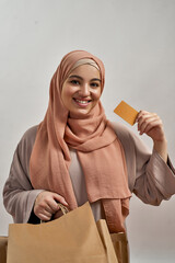 Happy young arabian woman with bags and paying card