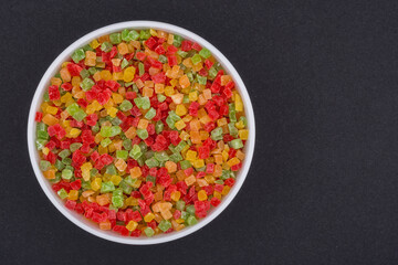 White glass bowl of candied fruit. Isolated on a dark grey background.