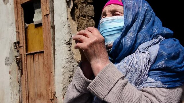 Masked grandmother on the background of the slums. Grandmother in a mask close-up. An elderly woman in a protective mask against the background of the ruins. An old grandmother in a protective mask.