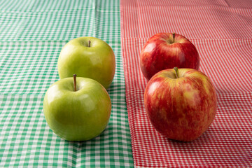 Green and red apples positioned on checkered towels, black background, selective focus.