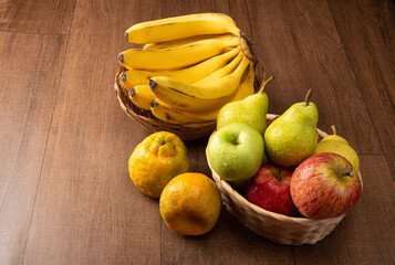 tropical fruit basket in detail on wooden surface, black background, selective focus.