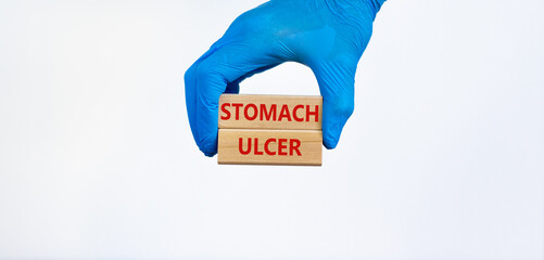 Stomach ulcer symbol. Doctor hand in blue glove holds wooden blocks with words 'Stomach ulcer'. Beautiful white background. Copy space. Medical and stomach ulcer concept.