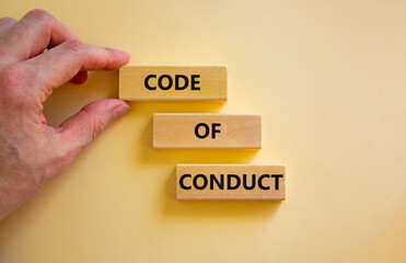 Code of conduct symbol. Concept words 'Code of conduct' on wooden blocks on a beautiful white background. Businessman hand. Business and code of conduct concept. Copy space.