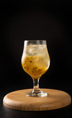 Brazilian Drink, Sake caipirinha with passion fruit in a bowl, on dark round wooden surface, black background, selective focus.