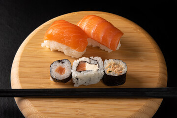 Sushi, beautiful sushi arrangement made of wood on dark surface, black background, selective focus.