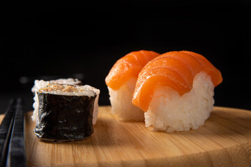 Sushi, beautiful sushi arrangement made of wood on dark surface, black background, selective focus.