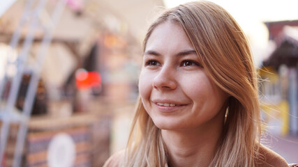 Portrait of a young woman in the city. City food court with street food. Portrait of a smiling blonde. Lifestyle photo