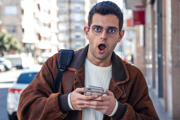 surprised man looking at mobile phone on the street