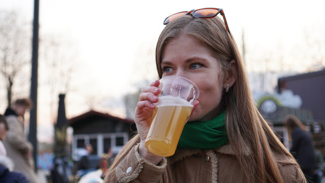 Young woman drinks light beer. Street food and food court. Lifestyle photo