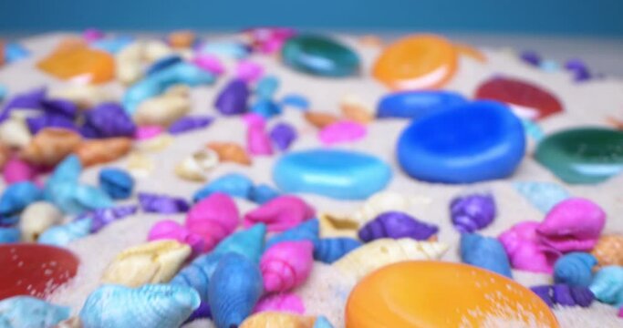 detailed extreme close-up of multicolored seashells and polished glass pebbles on white sand.