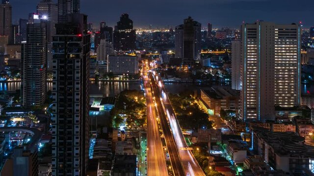Bangkok traffic toward downtown on Taksin bridge over Chao Phraya river at night, zoom out - time lapse