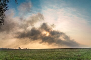 Umweltverschmutzung - dunkle Rauchwolken vor blauem Himmel am Horizont 