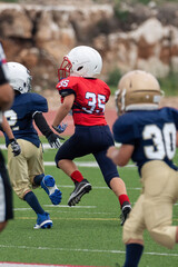 Young athletic boy playing in a youth tackle football game