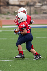 Young athletic boy playing in a youth tackle football game