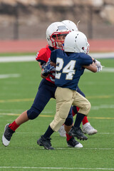 Young athletic boy playing in a youth tackle football game